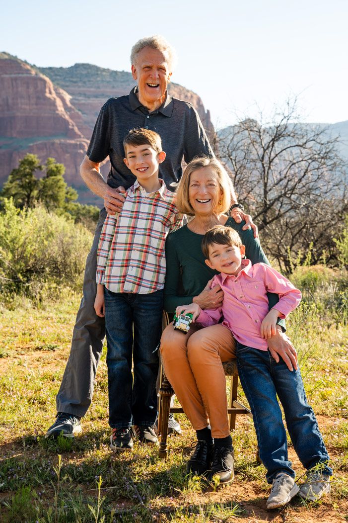 Multi-generational family poses together on hillside with Sedona red rock mountains in background.