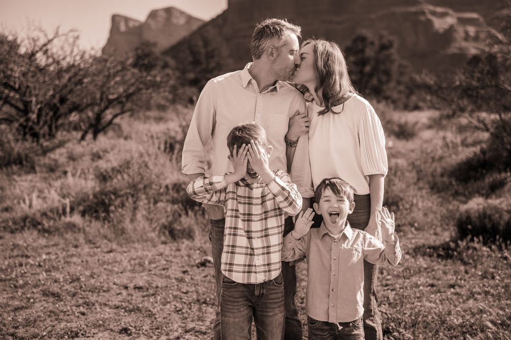 Family of four poses for black and white portrait with Sedona desert mountains in background.