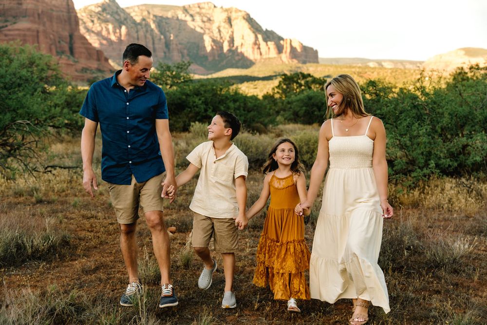 A family walks together through a scenic Sedona mountain landscape at sunset.
