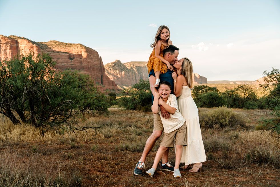Playful family poses outdoors against a backdrop of dramatic Sedona desert cliffs and mountains.