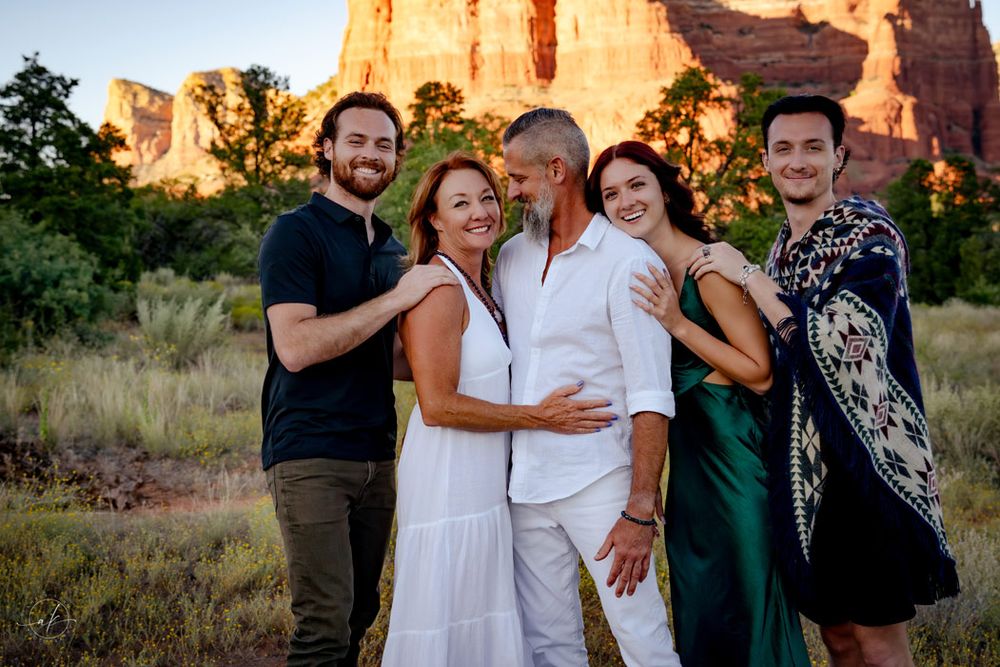 Group photo of friends embracing onSedona  red rocks with desert landscape behind them.