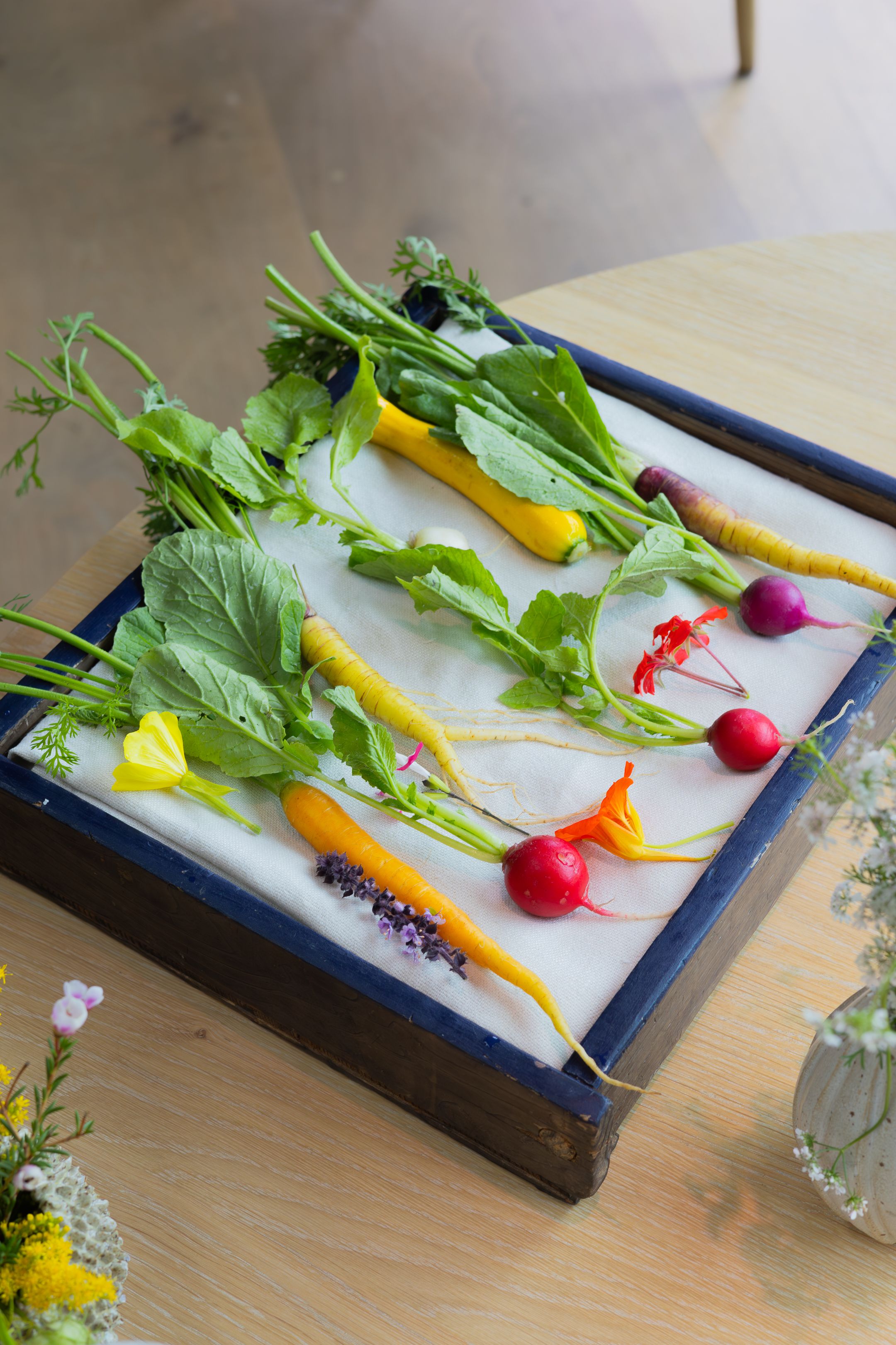 Colorful fresh vegetables and radishes artfully arranged on a blue serving platter.
