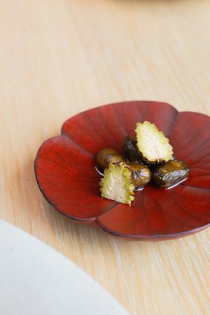 Roasted chestnuts displayed on a red decorative flower-shaped plate.
