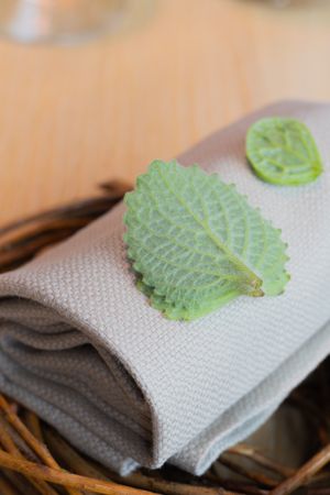 Fresh green herbs laid on a gray linen napkin in a woven basket.