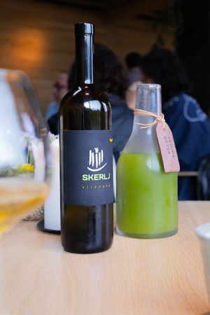 Wine bottle labeled Skeru next to green beverage on wooden table.