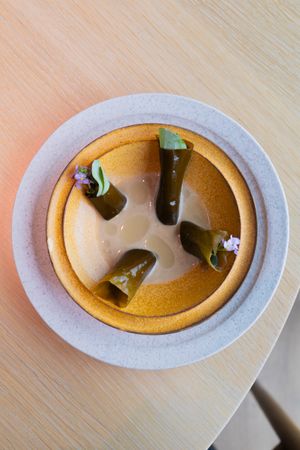 Green pickled vegetables arranged in creamy sauce on ceramic plate.