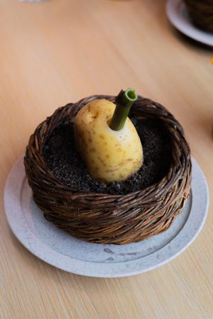 Decorative pear-shaped dessert nestled in a woven basket nest on a white plate.