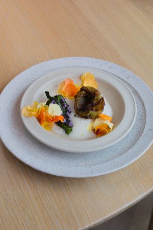 Artistically presented dish with orange and yellow garnishes on a double-stacked white plate.