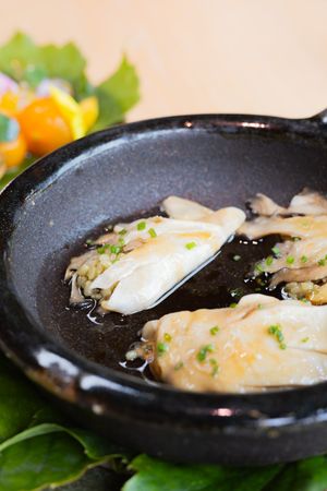 Close-up of pan-seared dumplings garnished with herbs in a black ceramic dish.