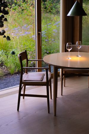 Intimate dining setting with round table, candles and wine glasses overlooking garden view.