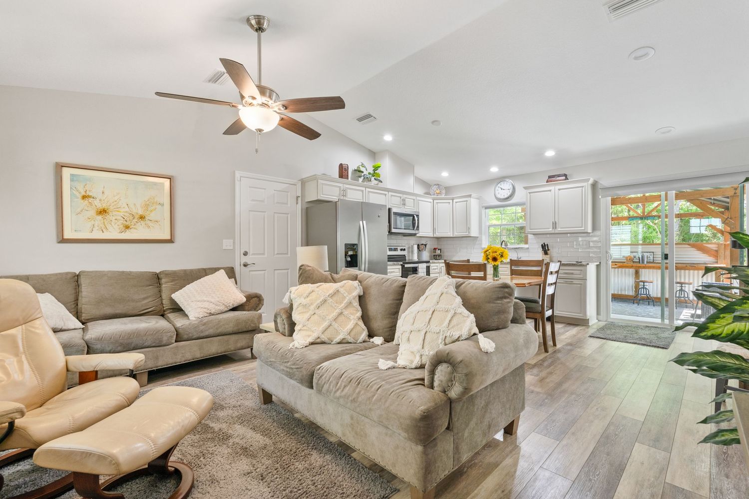Two story home on the bay with green lawn and shady oak trees.