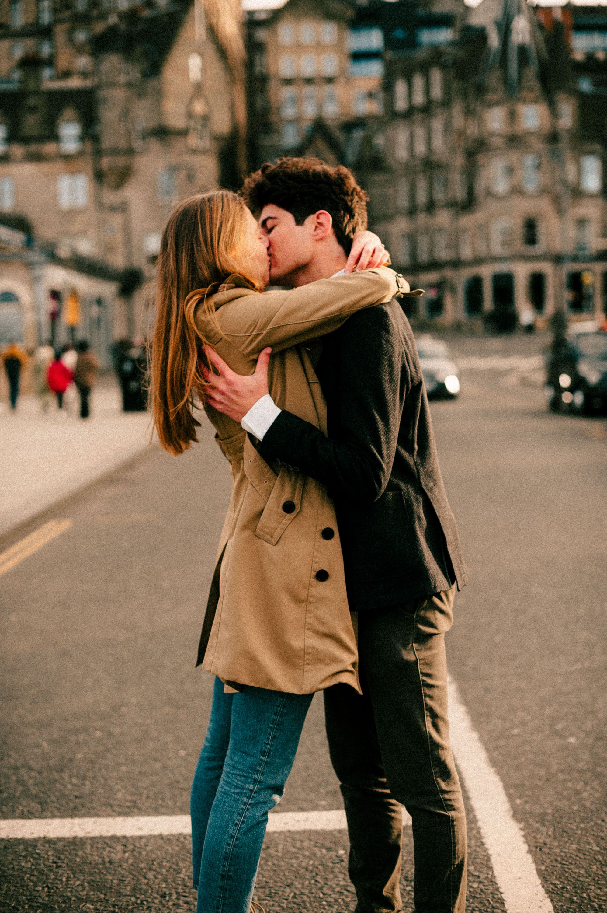 An intimate embrace on a city street with classic Scottish architecture in the background.