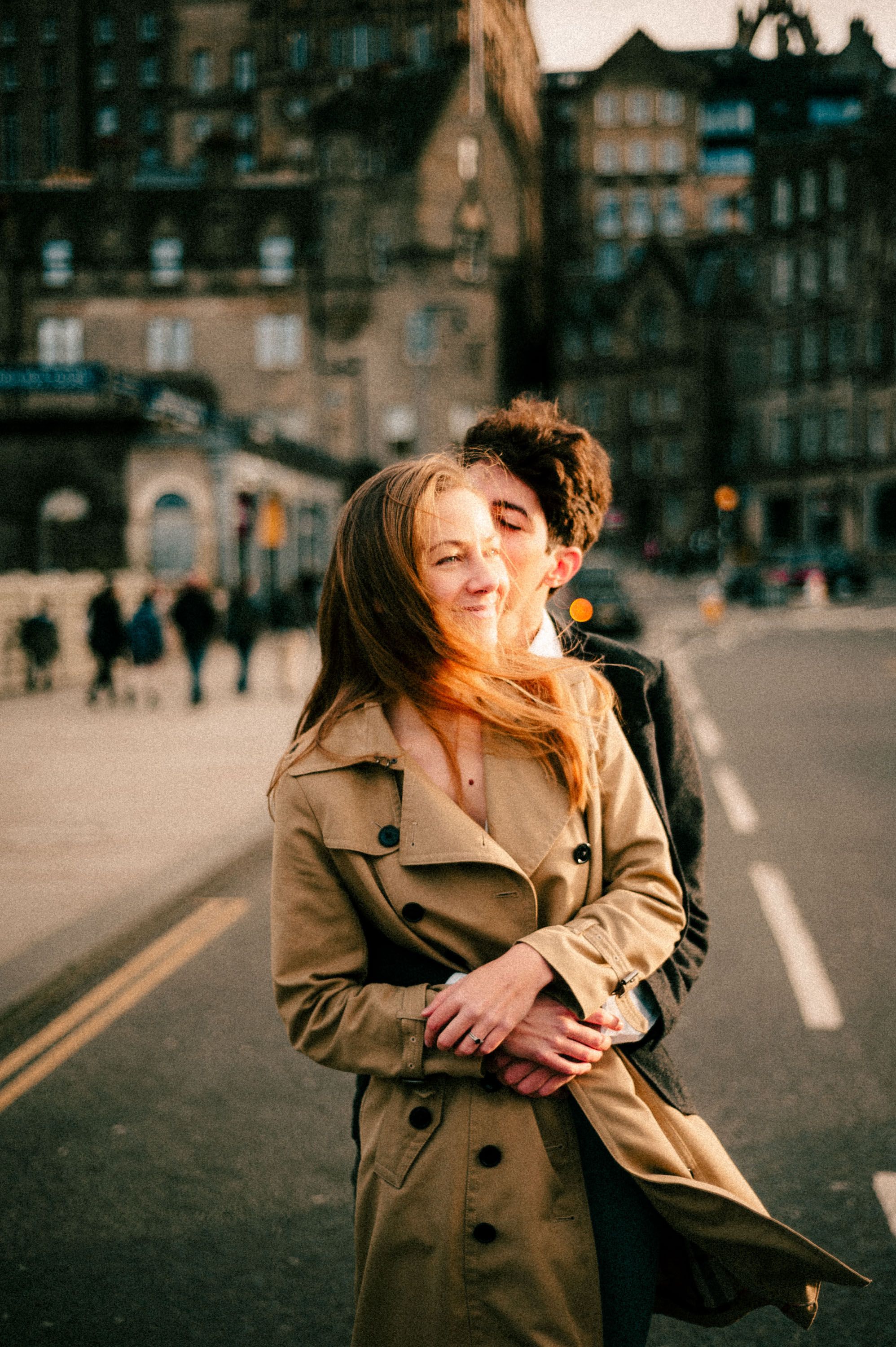 A joyful moment captured on an Edinburgh street with wind-blown hair and genuine laughter.