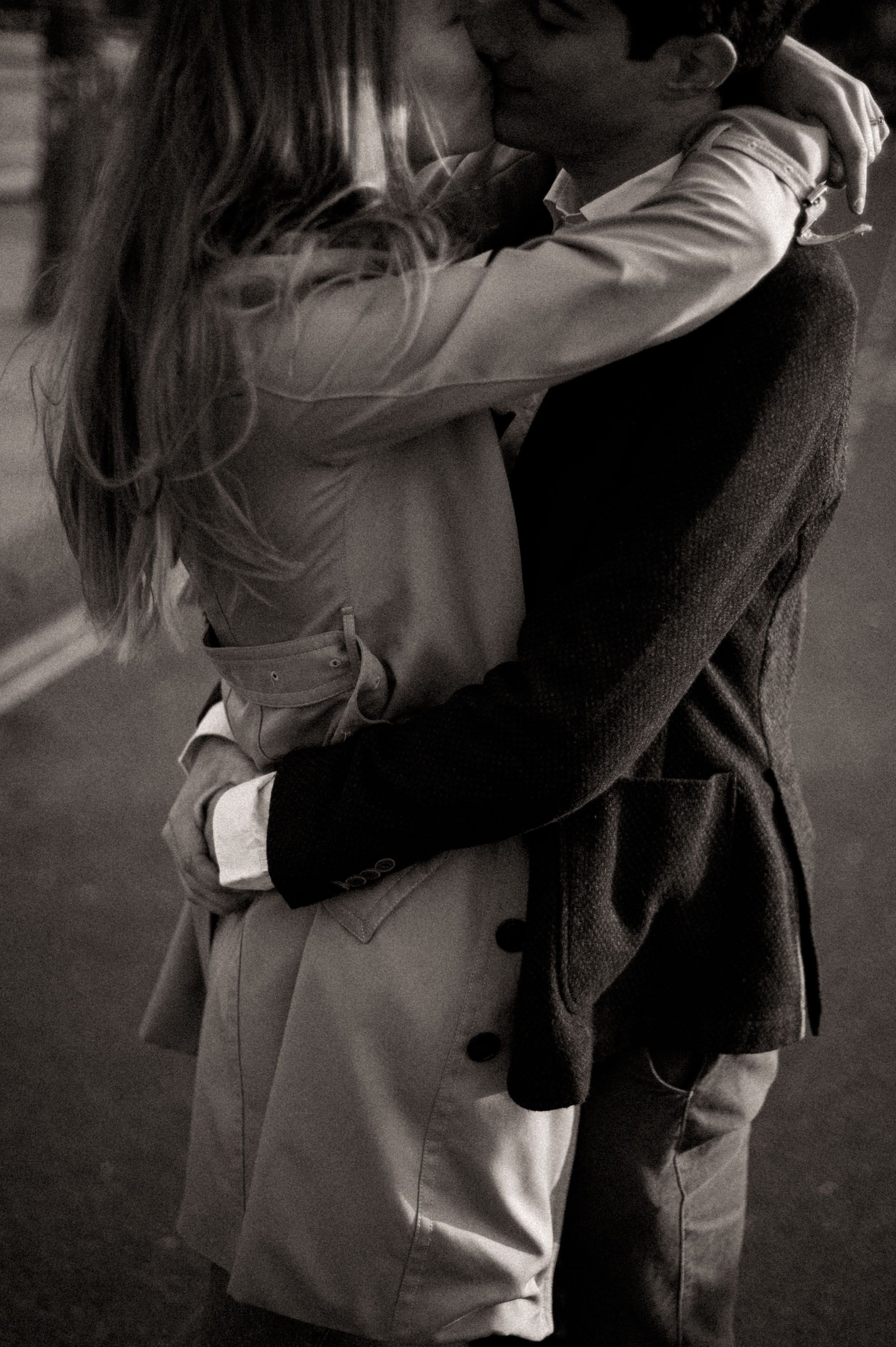 A black and white photograph of an intimate embrace on a city street.