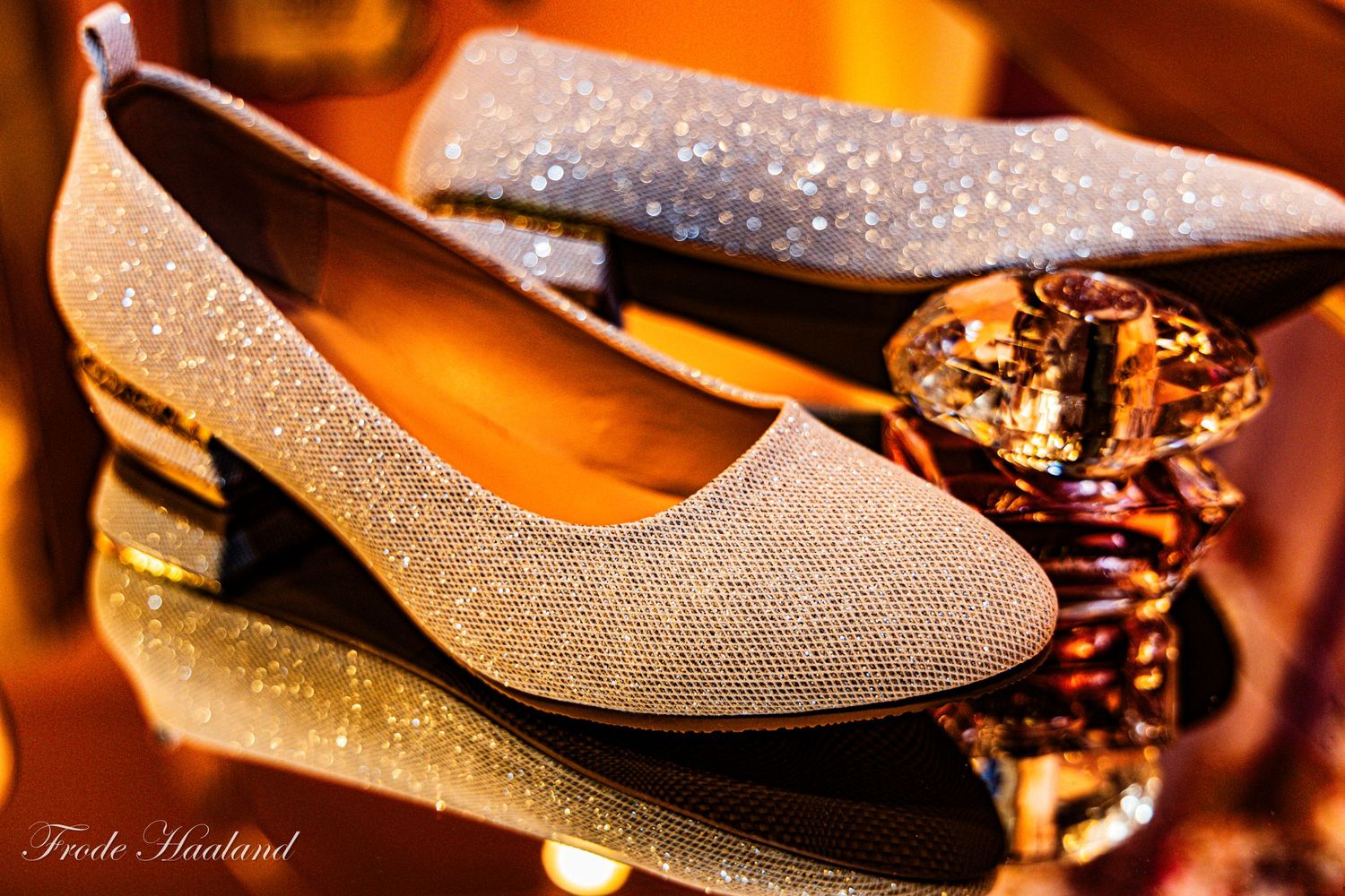 Sparkling silver glitter bridal flat shoes displayed with crystal decorations in warm light.