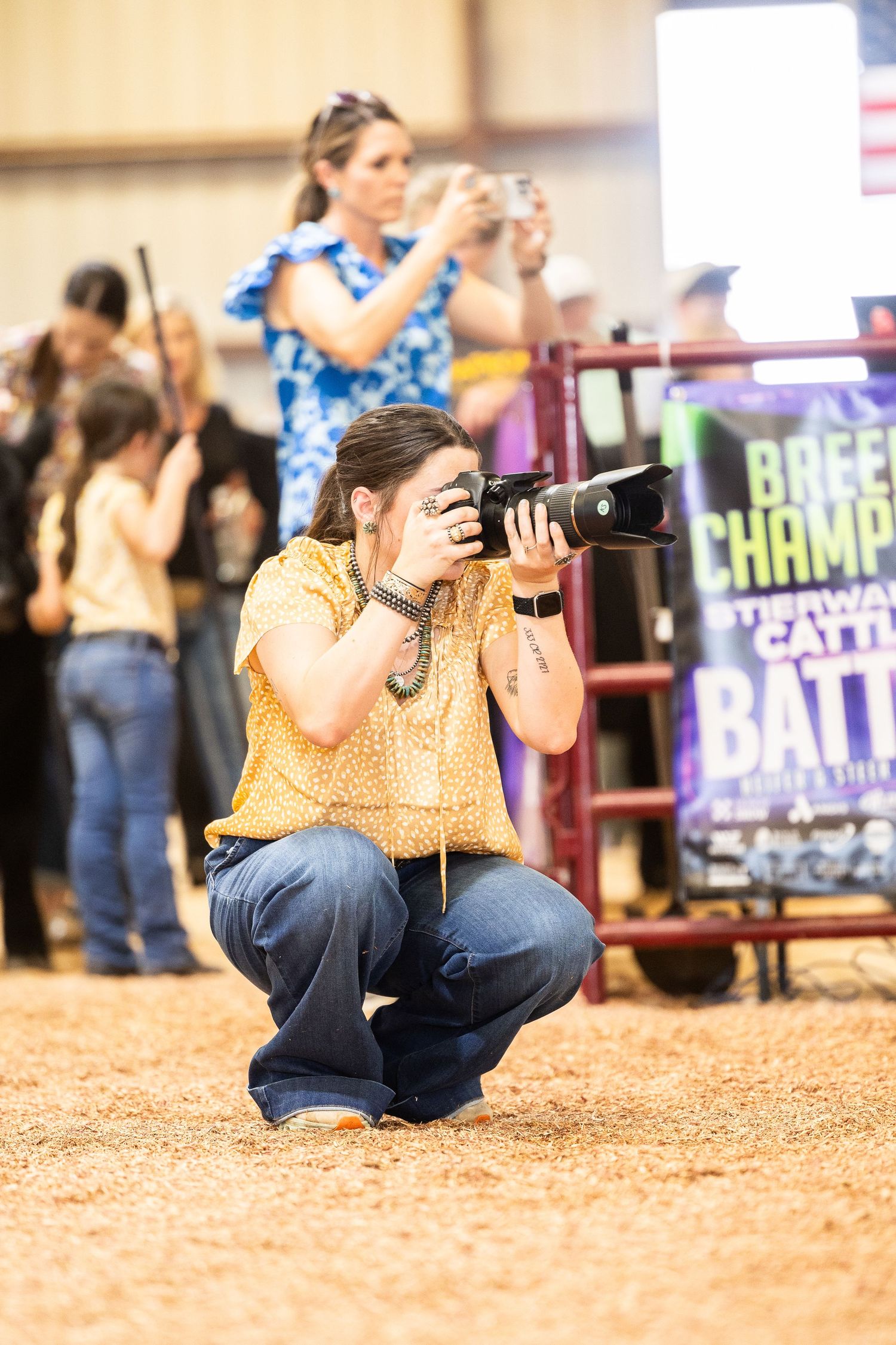 Photographers capturing moments at a livestock event in an indoor arena.
