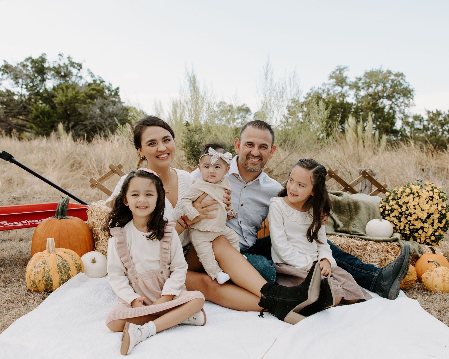 San Antonio Family Photography. Family sitting on blanket outdoors with pumpkins and fall decorations.