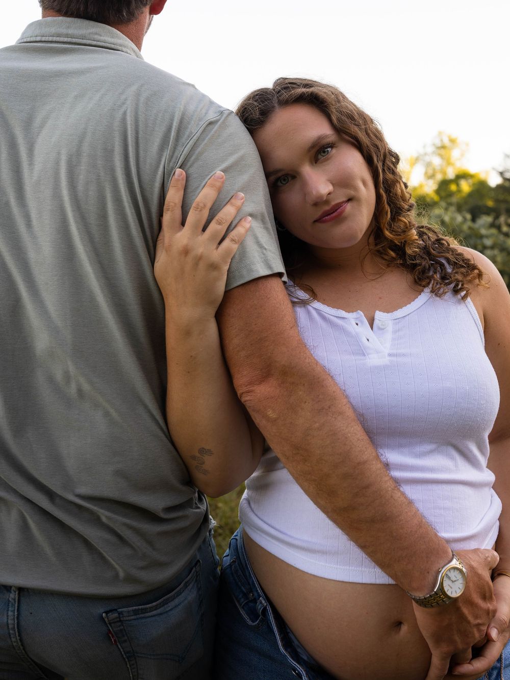 Intimate couple embracing in casual attire during outdoor photoshoot.