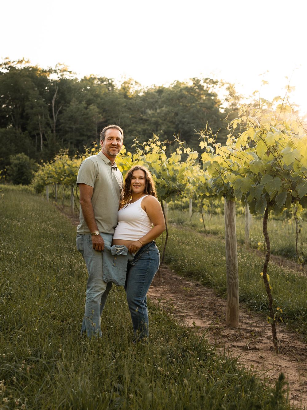 Couple walking through vineyard during golden hour photography session.