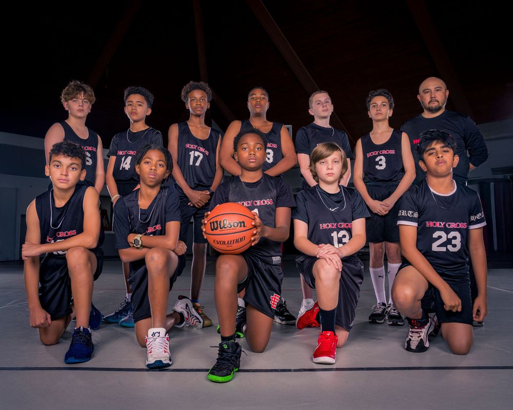 Youth basketball team in navy blue uniforms posing for a group photo with a basketball.