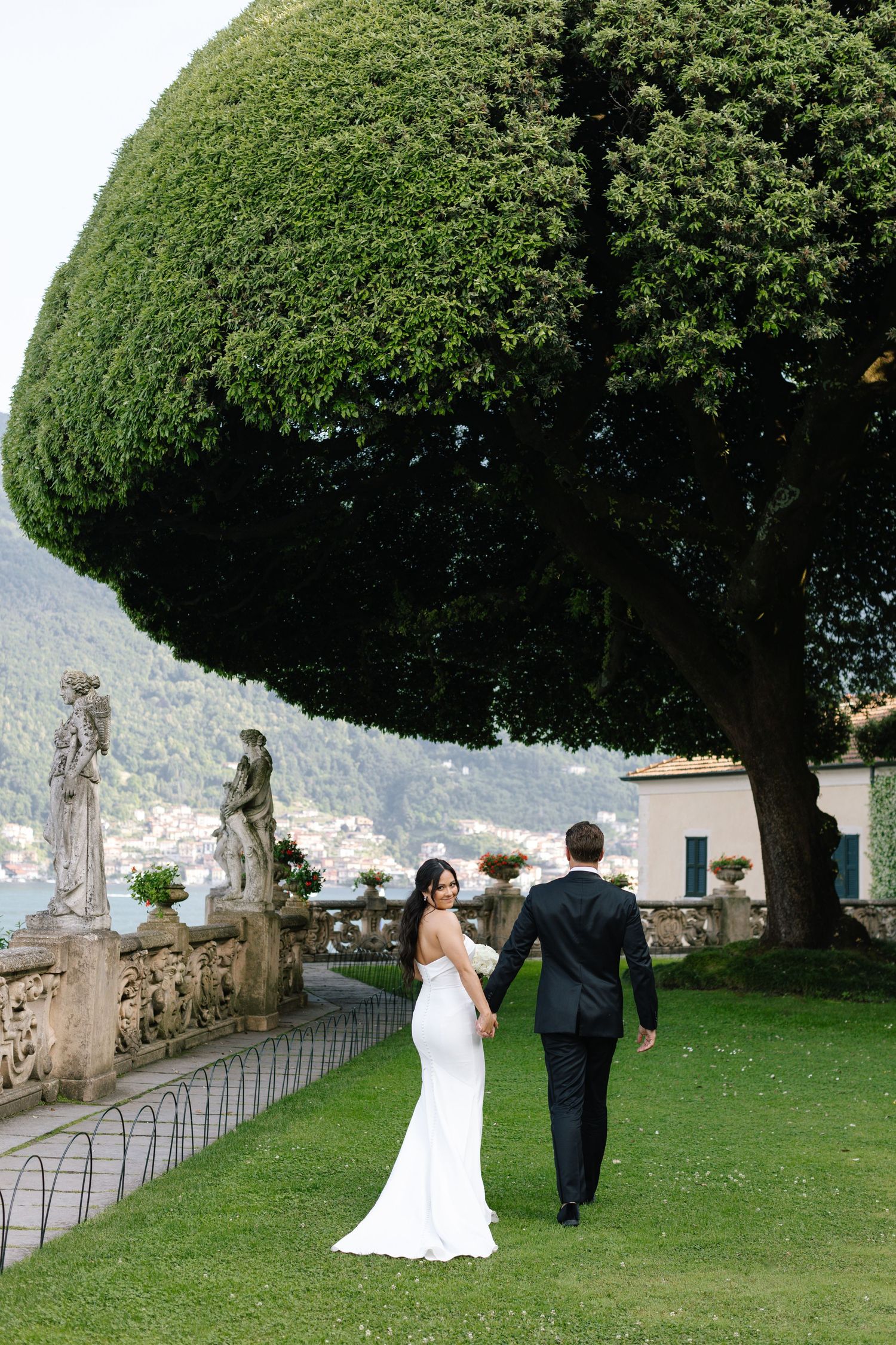 Playful moment with wedding veil covering bride's face in black and white photo.