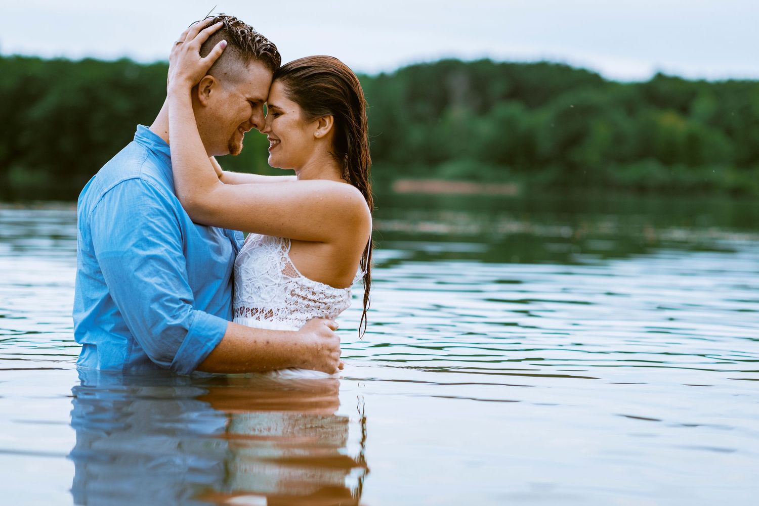 Romantic couple embracing in a lake during an outdoor engagement photo session.
