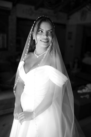 An elegant bridal portrait showing a flowing white wedding dress and veil in black and white.