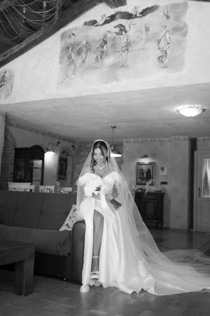 Elegant wedding gown with flowing veil captured in a black and white photograph of a dance hall.