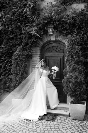 Classic black and white bridal portrait in front of an ivy-covered doorway with an ornate lantern and flowing veil.
