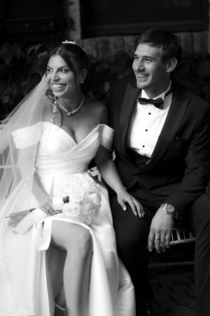 Wedding couple shares a joyful candid moment in classic black and white photography style.