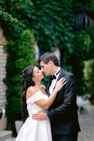 Romantic wedding moment captured in front of lush green foliage backdrop.