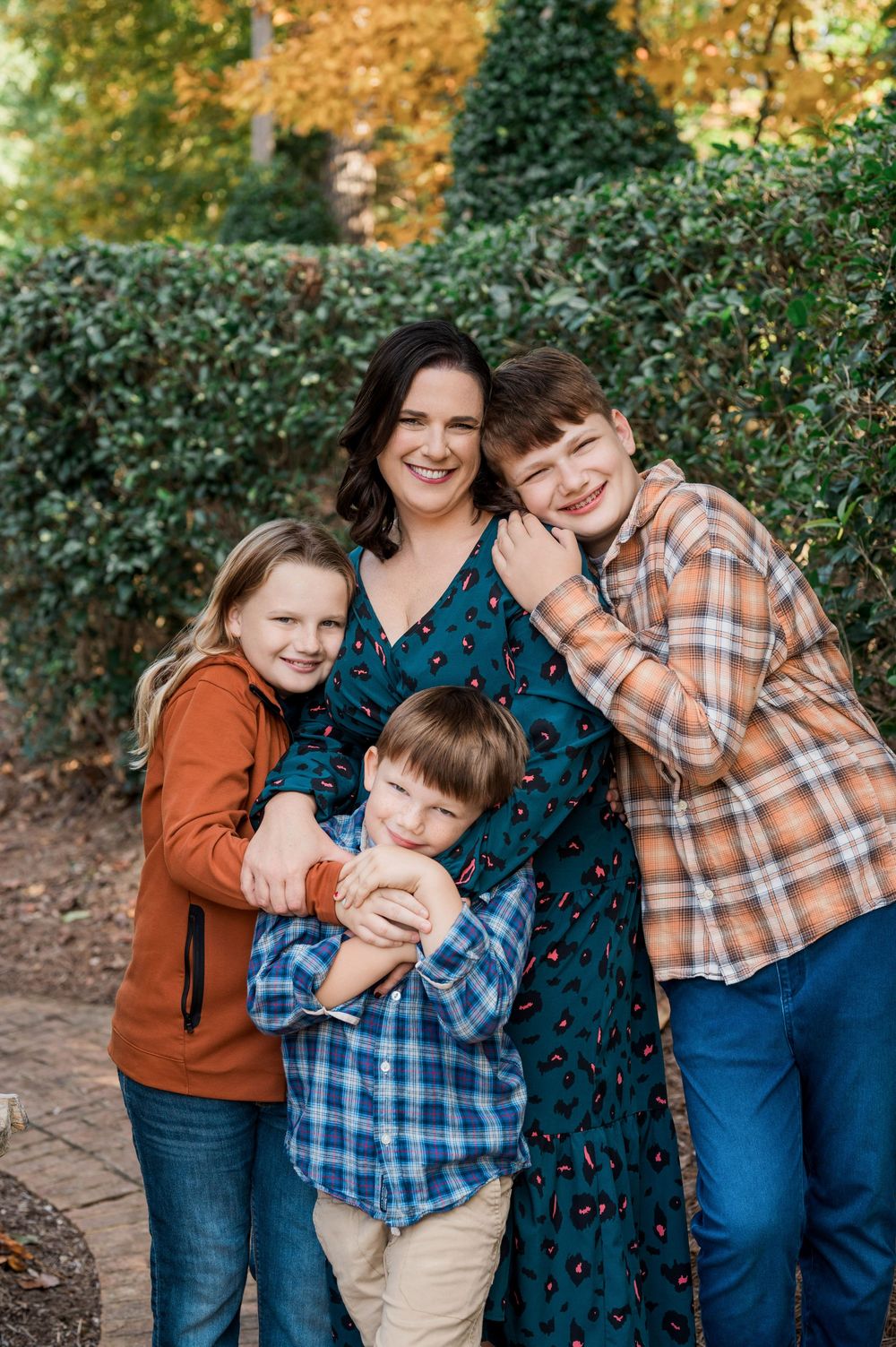 A family shares joyful moments together during an outdoor autumn photoshoot with warm fall colors and greenery.