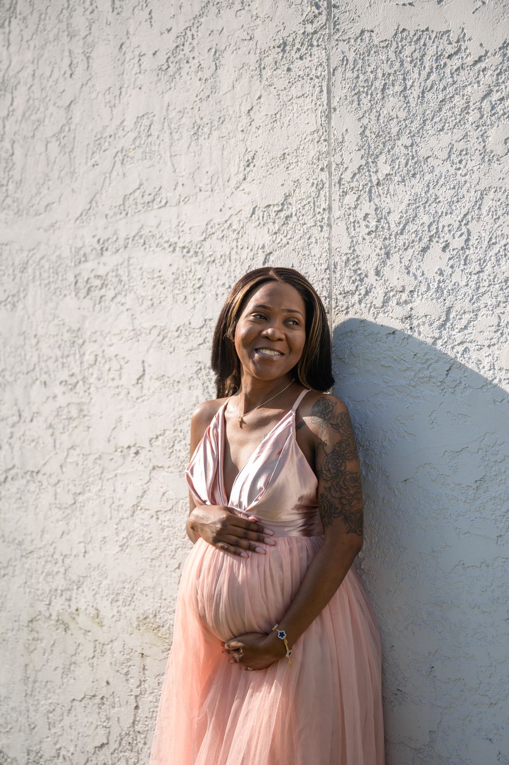 A glowing maternity portrait against a textured white wall.