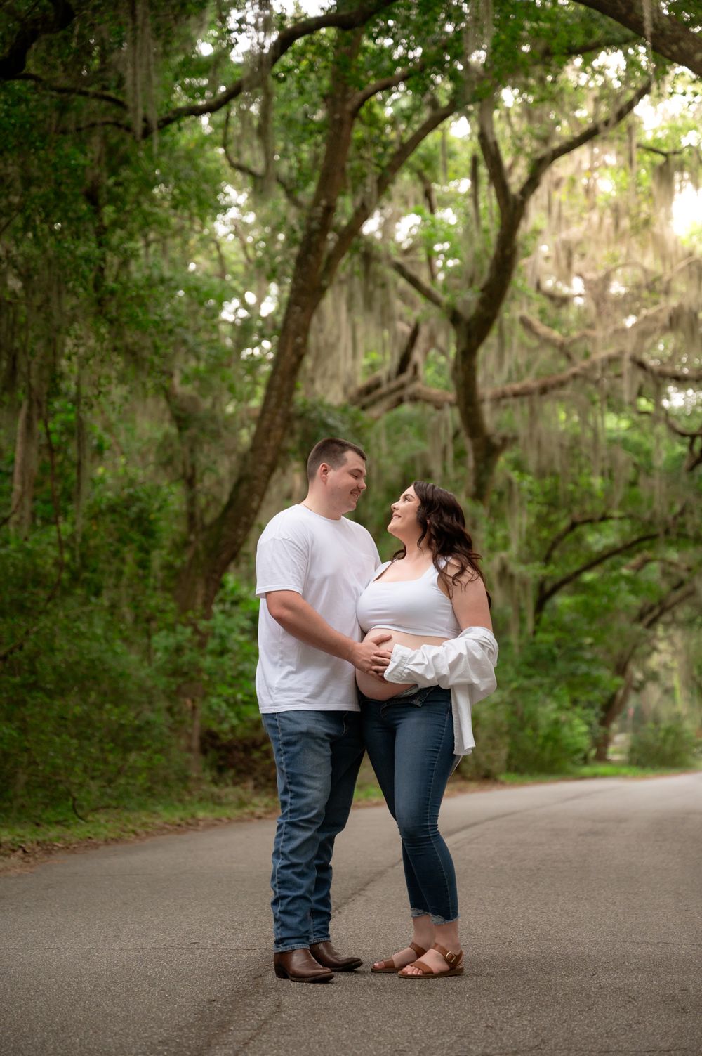 A tender maternity moment captured on a tree-lined path.