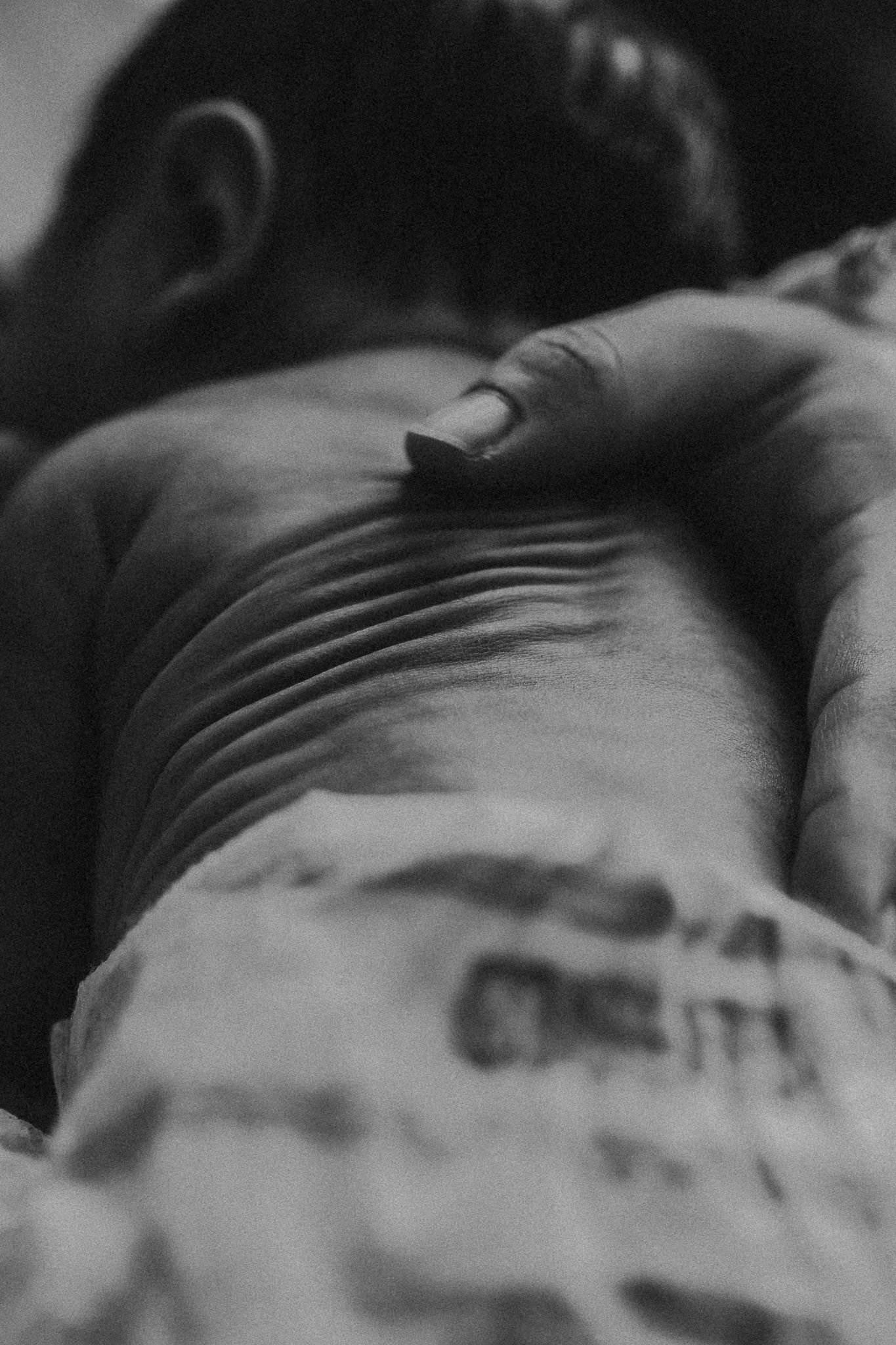 Dramatic black and white portrait of newborn during medical care.
