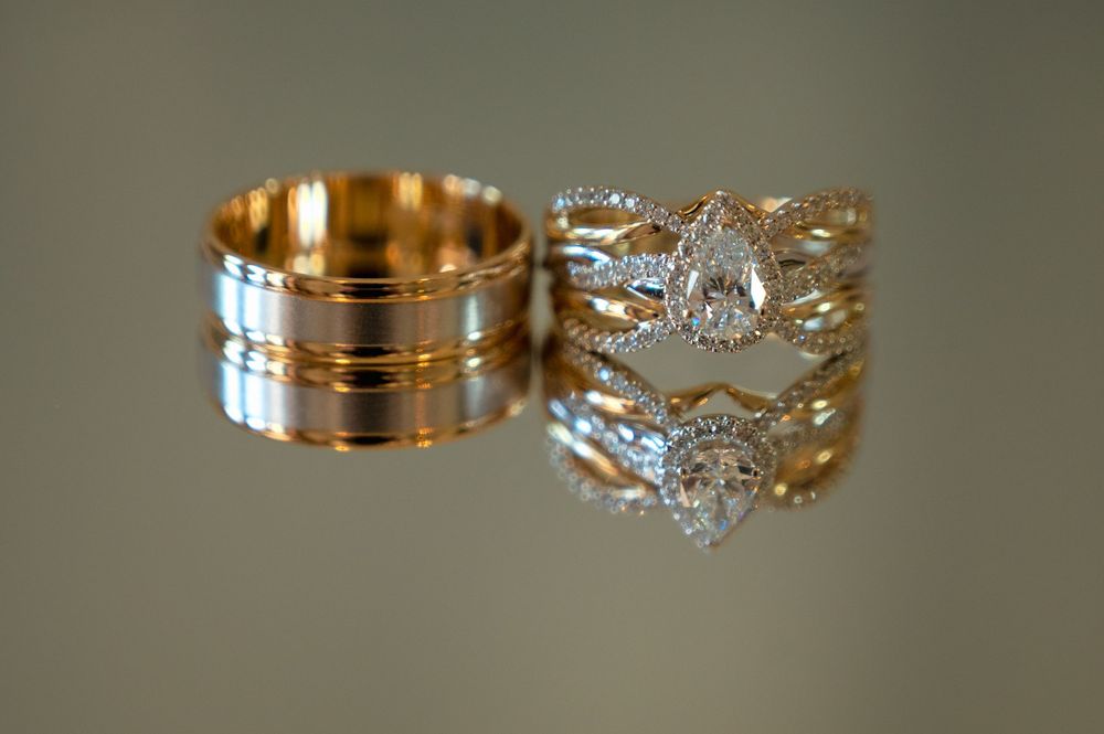 Two elegant wedding rings on display, one gold band and one ornate diamond ring with intricate details.