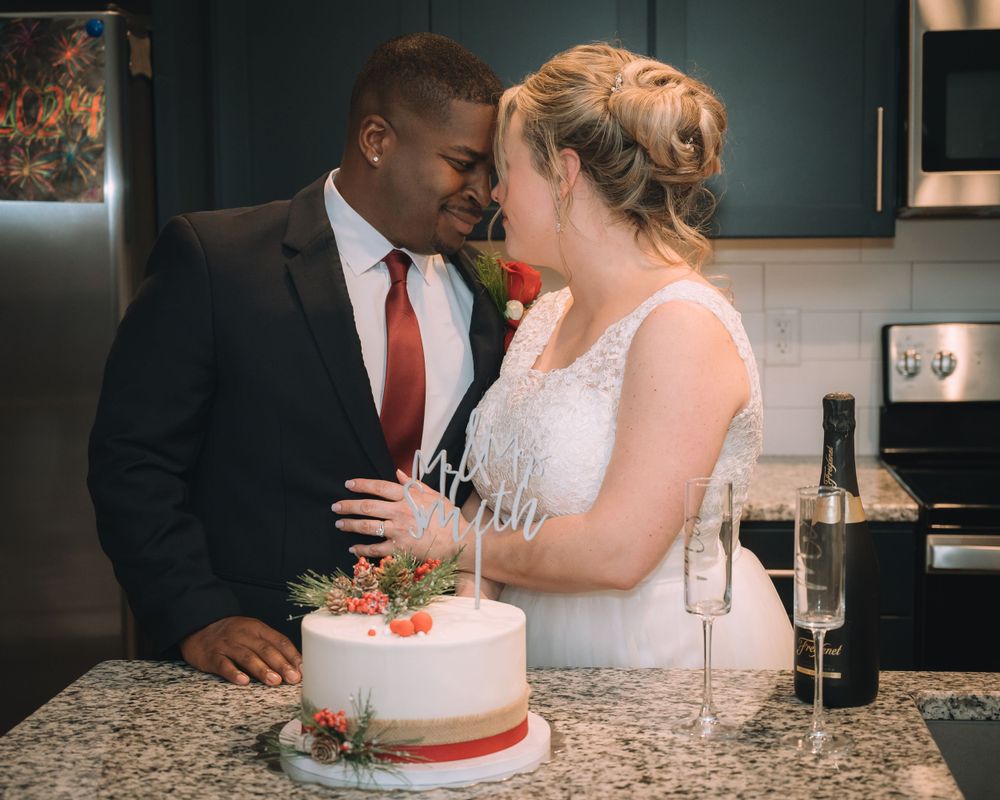 Couple sharing intimate moment over wedding cake in kitchen setting.