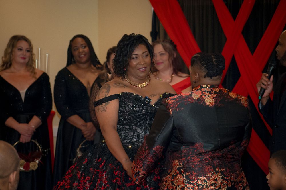 Group of wedding guests in formal black and red dresses at an evening celebration.