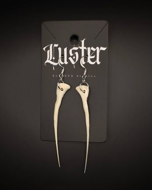 Long white bone-styled earrings on black Luster brand display card.
