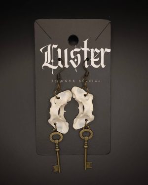 Vintage-style earrings featuring white bone elements and antique keys on black display card.