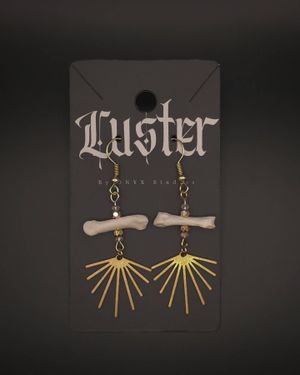 Gothic bone and brass sunburst earrings displayed on black branded jewelry card.