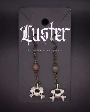 Gothic earrings featuring small skulls and beads on a dark branded display card.