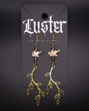 Delicate brass leaf branch earrings with bone detail on black display card.