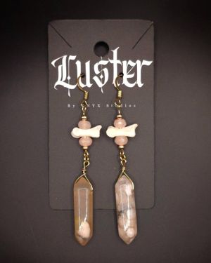 Crystal point earrings with bone fragments and pink beads on gothic display card.