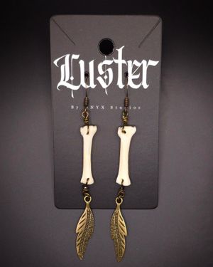 Bone and feather dangle earrings with brass accents displayed on gothic style card.