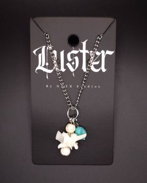 Silver chain necklace with bone fragments and turquoise stone charms on gothic display card.