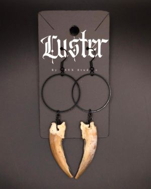 Gothic style hoop earrings featuring large animal tooth pendants on black display.