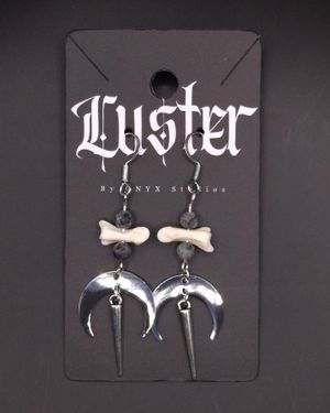 Gothic earrings featuring small bone charms and silver crescent moon pendants on black display card.