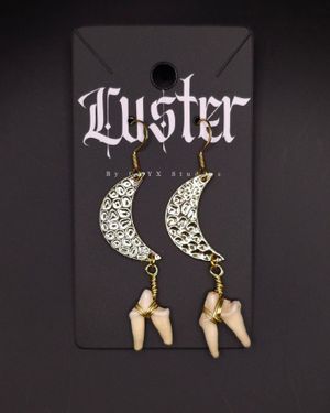 Decorative crescent moon earrings with bone charms displayed on gothic-style card.