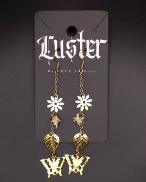 Gothic earrings with flower and leaf charms hanging from brass chains on black display.
